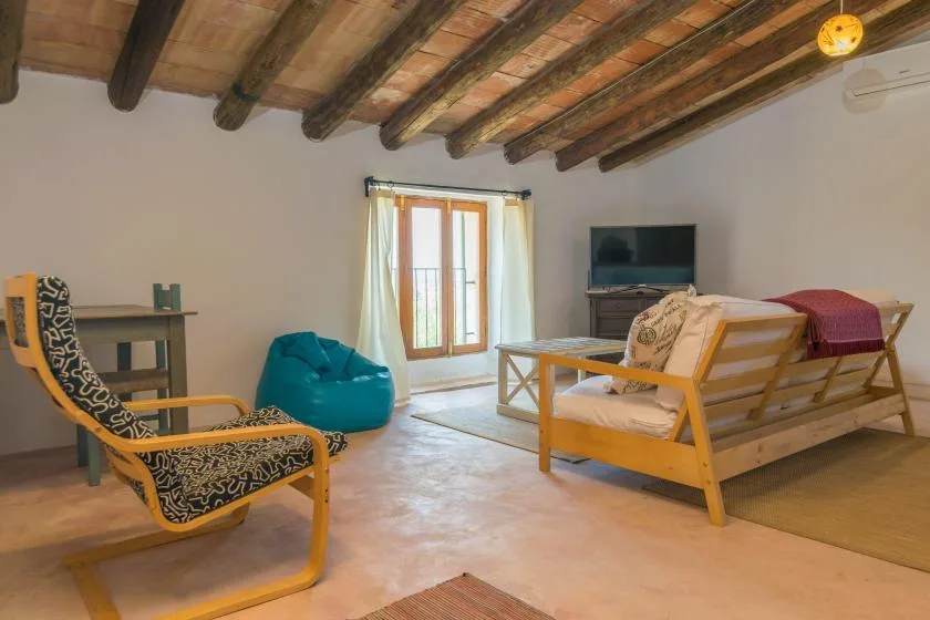 A living room with seating, a television, and doors opening onto a balcony.