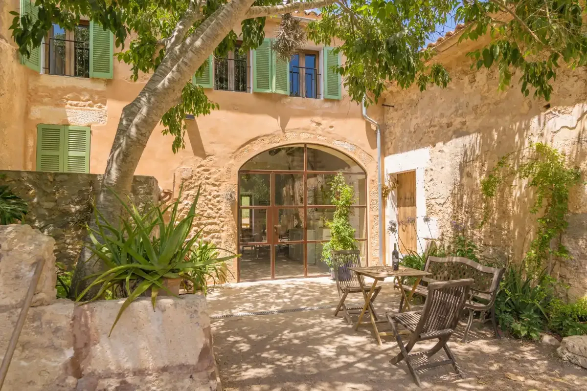A stone courtyard with outdoor seating beneath a leafy tree.