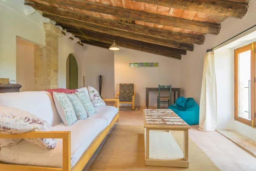A bright living room with seating, a coffee table, and exposed ceiling beams.