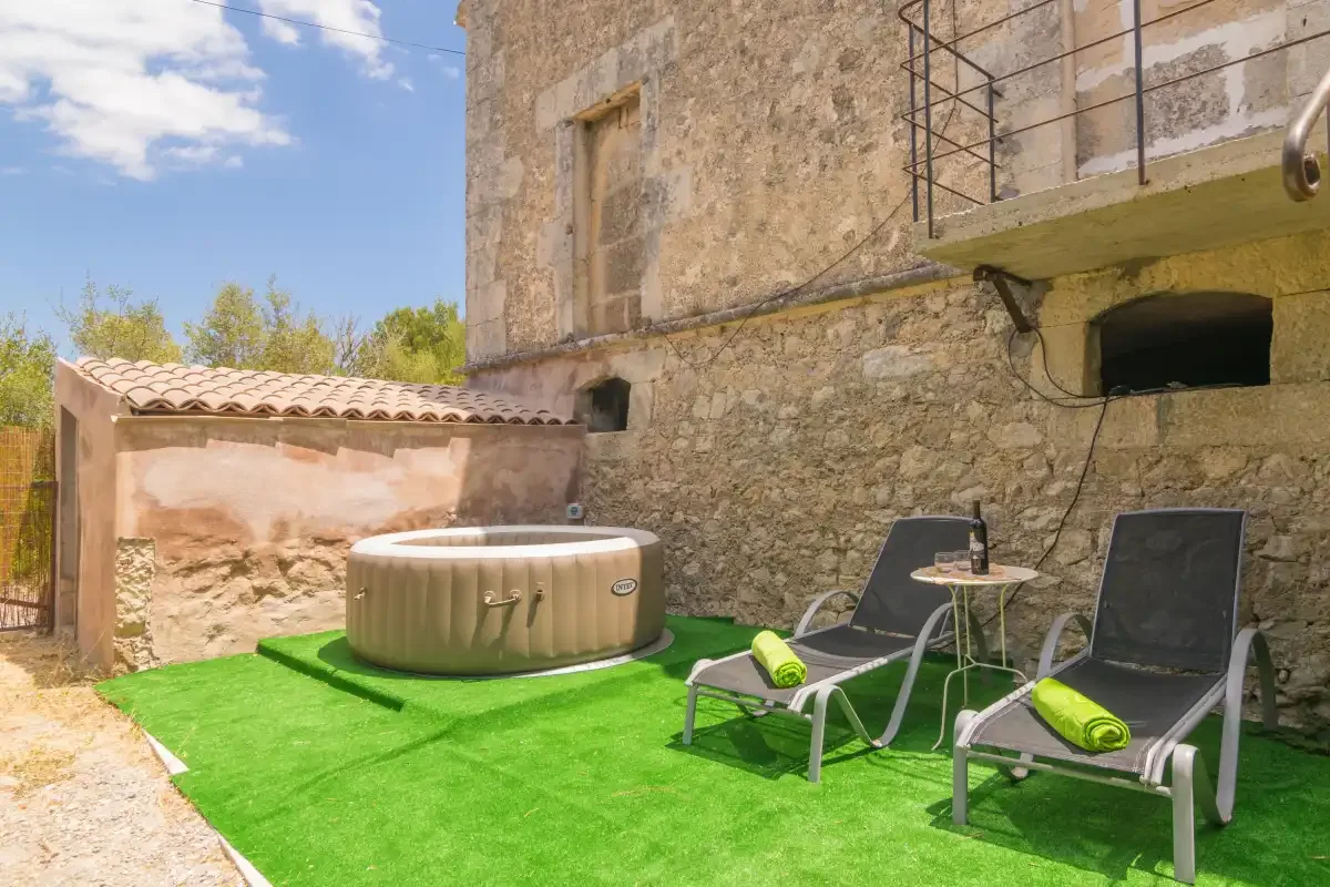 A sunny outdoor patio with a round hot tub and lounge seating.
