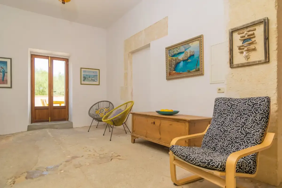 A bright sitting room with patterned seating and a wooden chest.