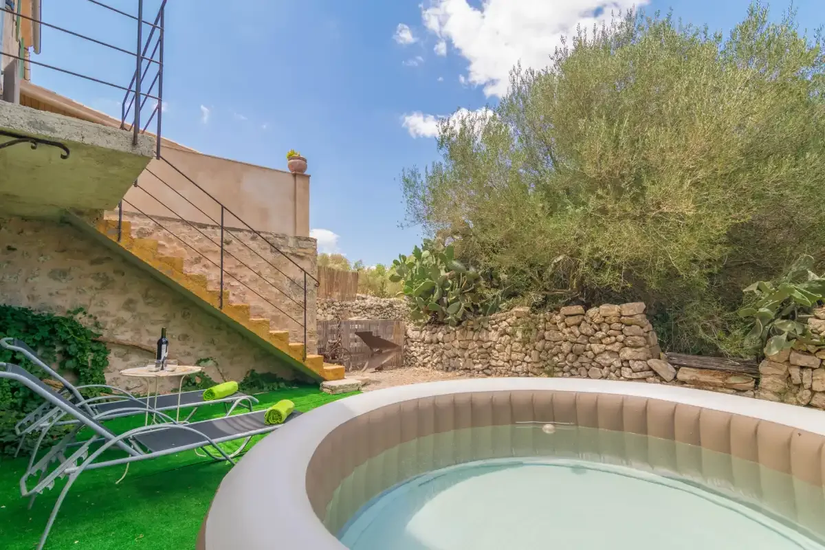 An outdoor pool sits beside a stone retaining wall and garden.