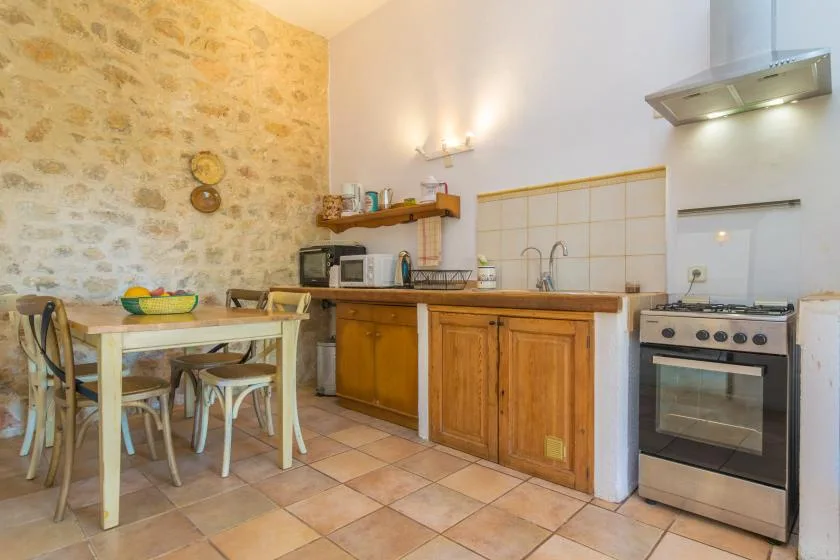 A rustic kitchen with wooden cabinets, a dining table, and a stove.
