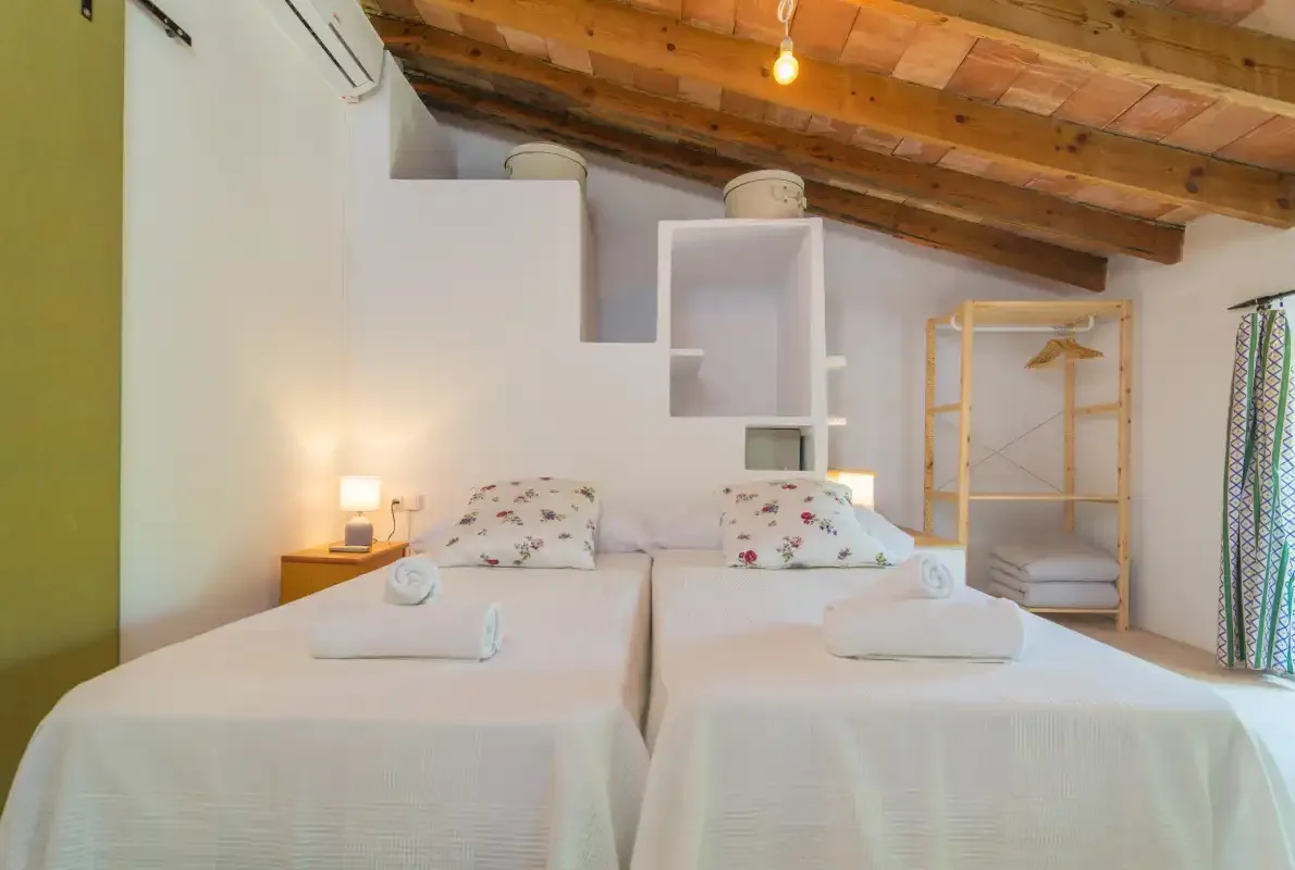 A bedroom with two beds beneath a sloped wooden ceiling.
