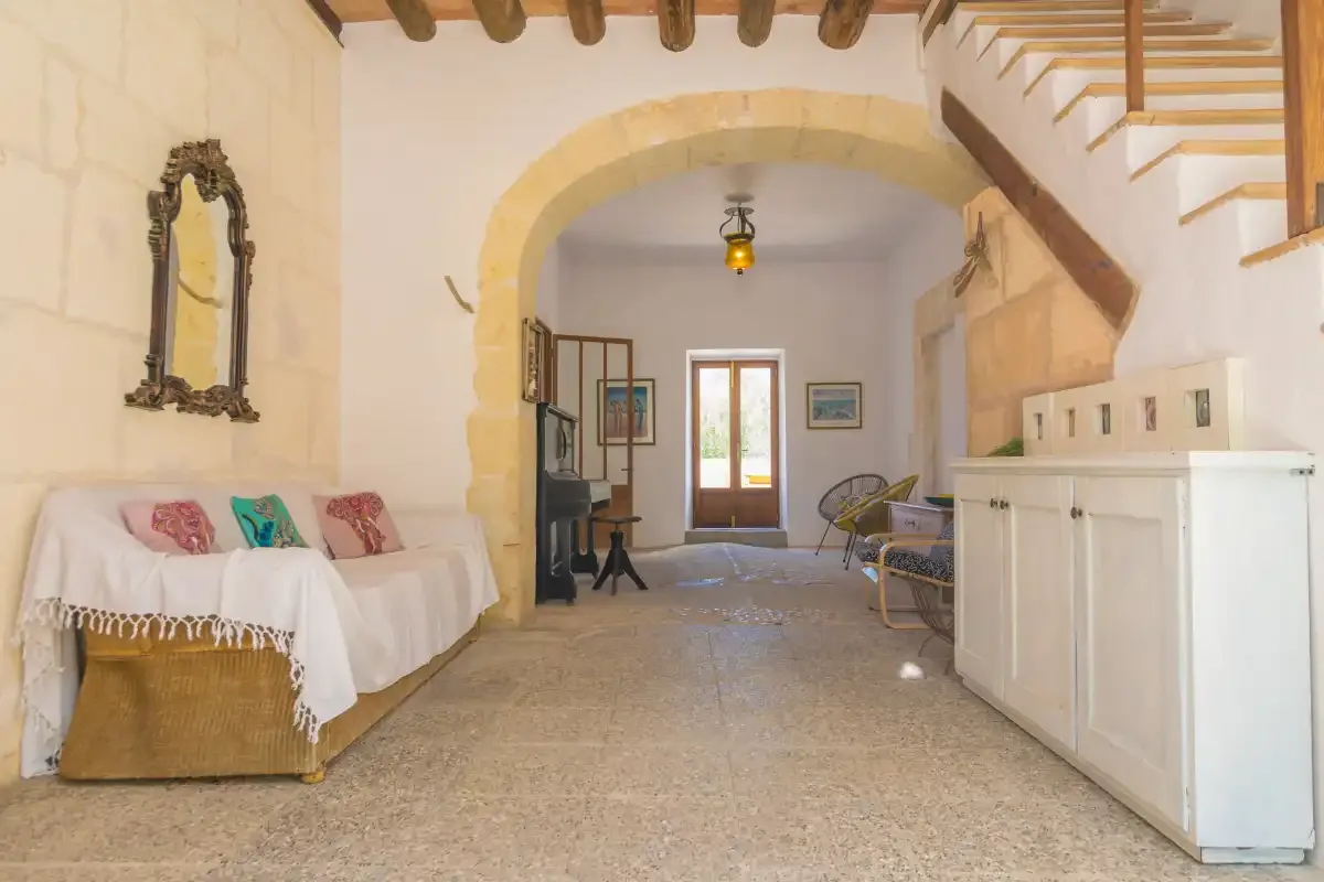 A stone interior hallway with seating, a white cabinet, and stairs.