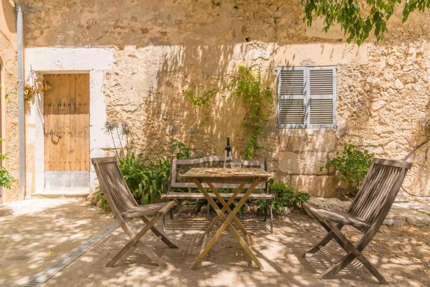 An outdoor patio with a wooden table and seating beside a stone wall.