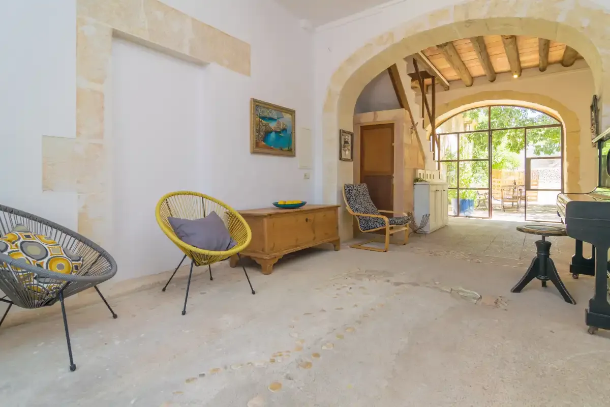 A bright living room with an arched opening and colorful seating.