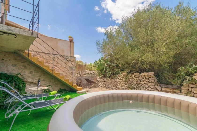 An outdoor hot tub sits beside a stone retaining wall and garden stairs.