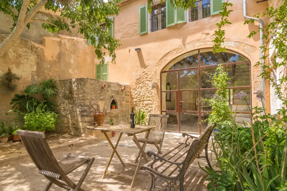 A sunny courtyard with outdoor seating and a large arched glass doorway.