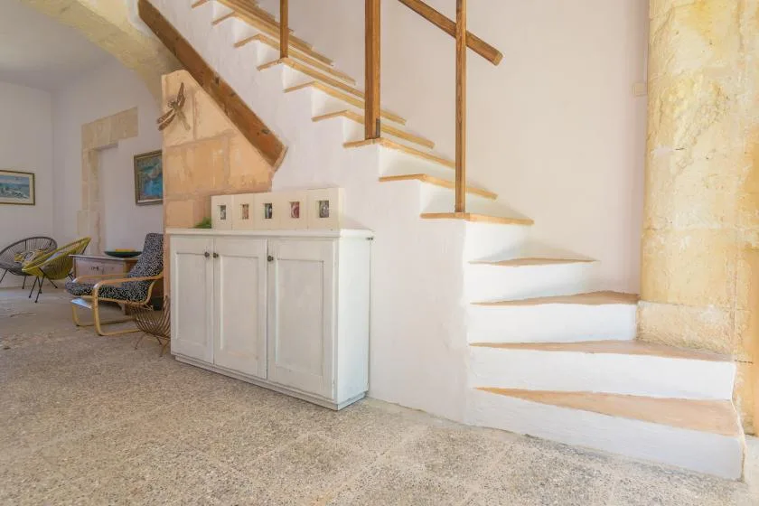 An indoor staircase with wooden handrails rises beside a built-in cabinet.