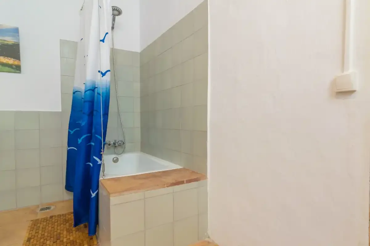 A tiled bathroom with a bathtub and blue shower curtain.