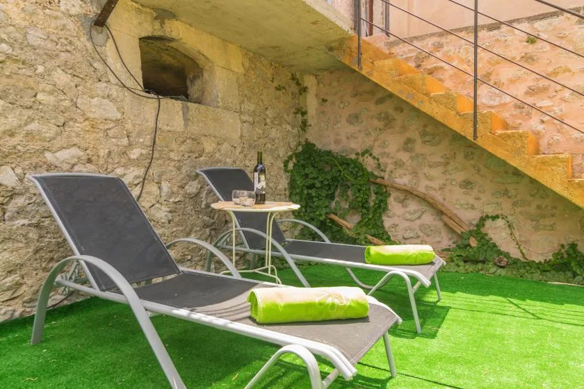 An outdoor seating area with reclining loungers, a small table, and green artificial turf.