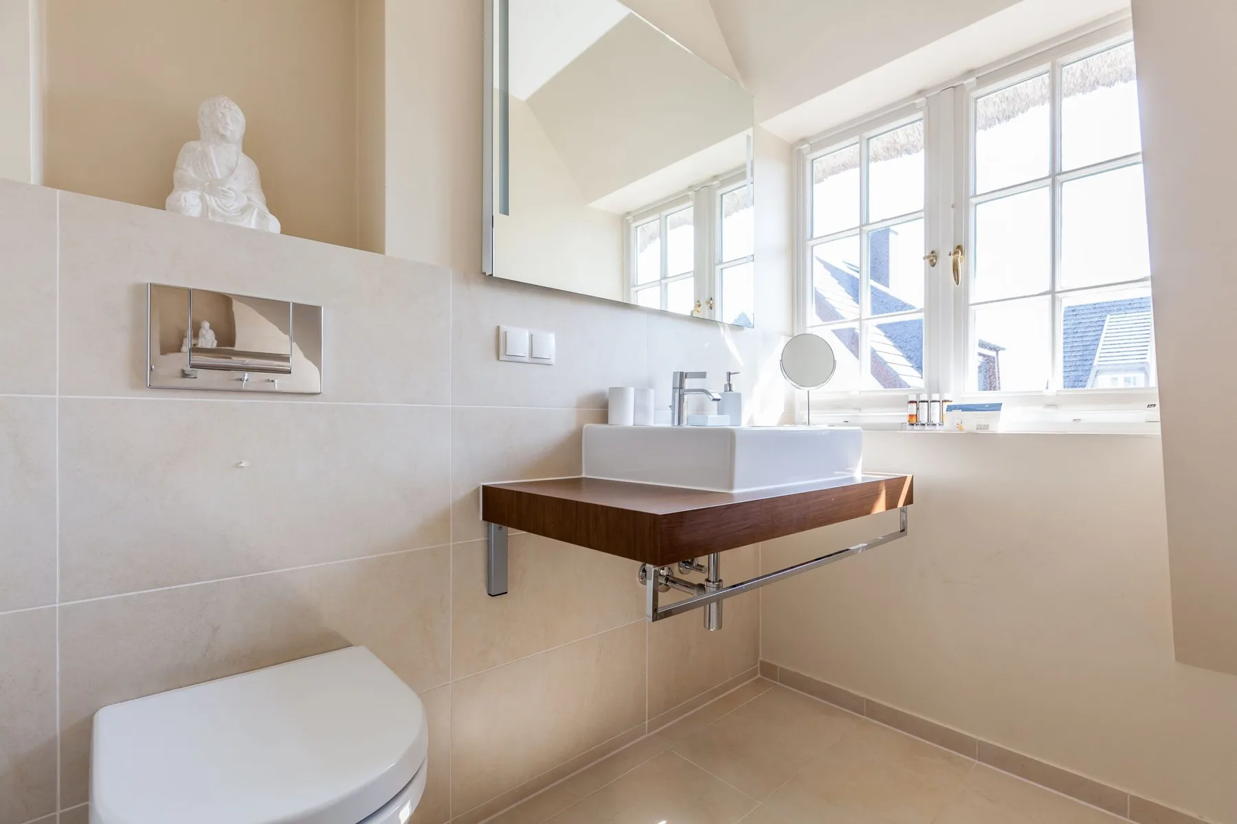 Un baño luminoso con un lavabo suspendido bajo grandes ventanas.