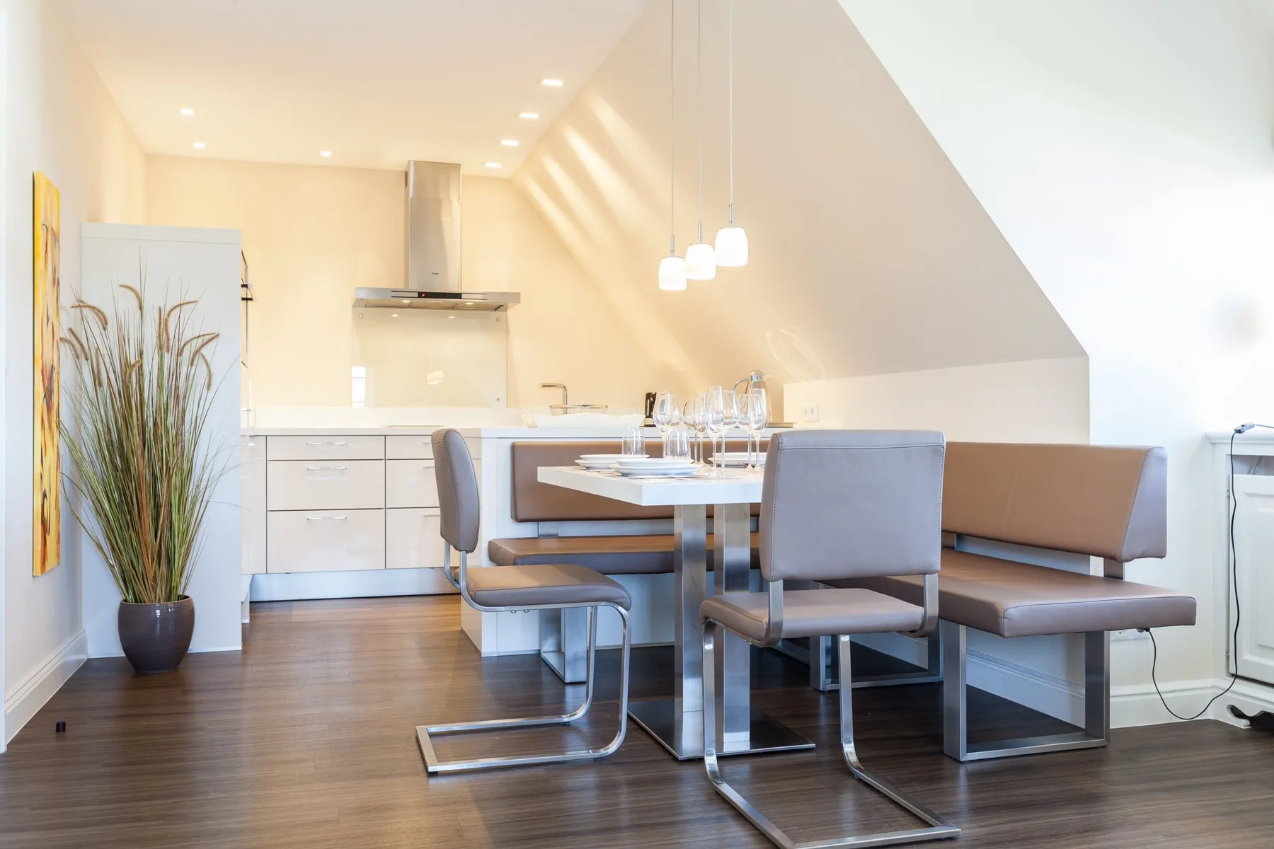 Comedor con mesa y asientos tipo banco junto a una cocina luminosa.