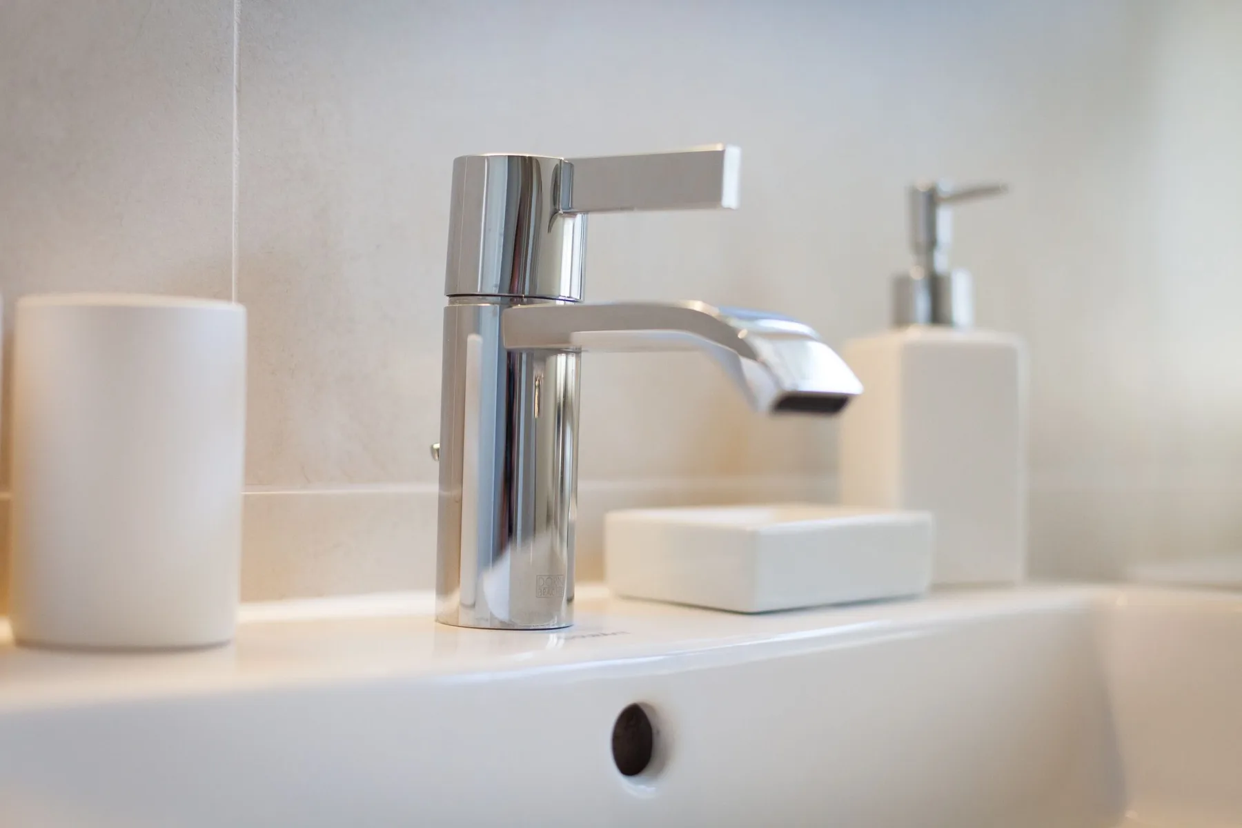 Un lavabo de baño con un grifo cromado y una jabonera pequeña.
