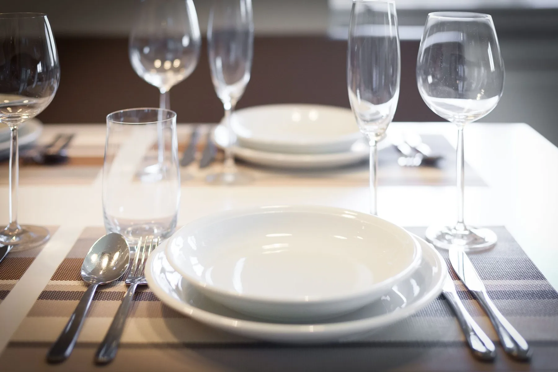Una mesa está puesta con platos, copas y cubiertos.