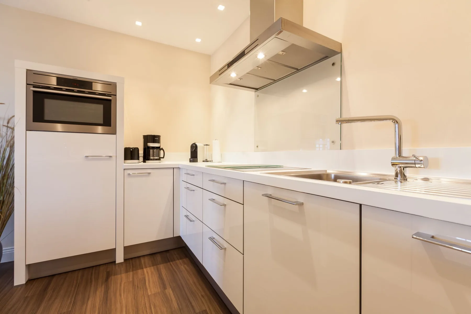 Una cocina moderna con gabinetes blancos, un horno empotrado y una encimera.