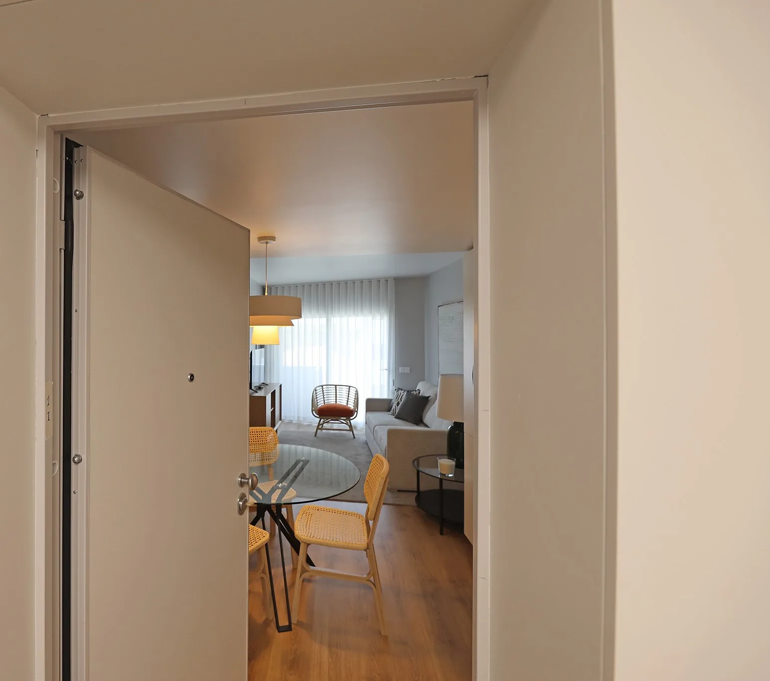 An open doorway looks into a living room with seating and a dining table.
