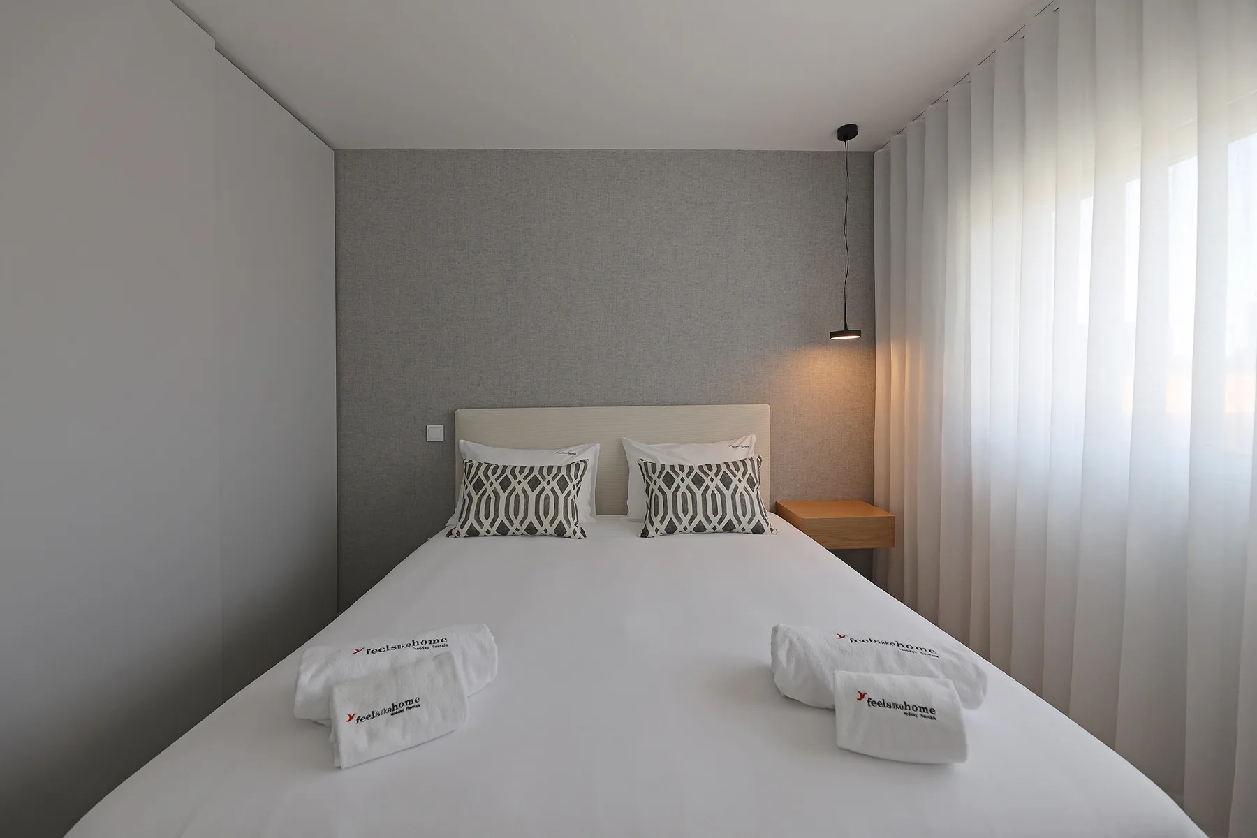 A bedroom with a neatly made bed and patterned pillows.