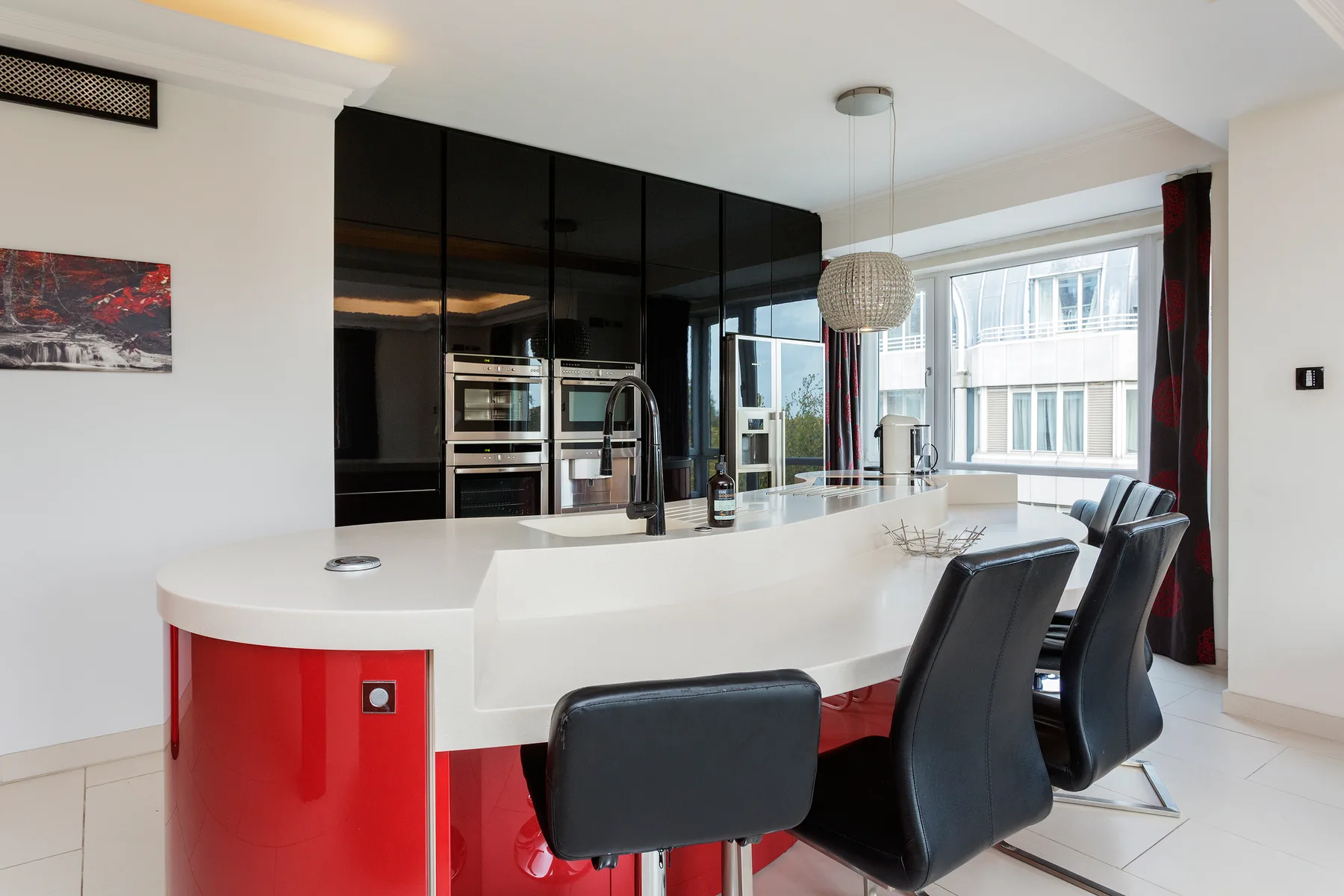 A modern kitchen with a curved island, dark cabinetry, and large windows.
