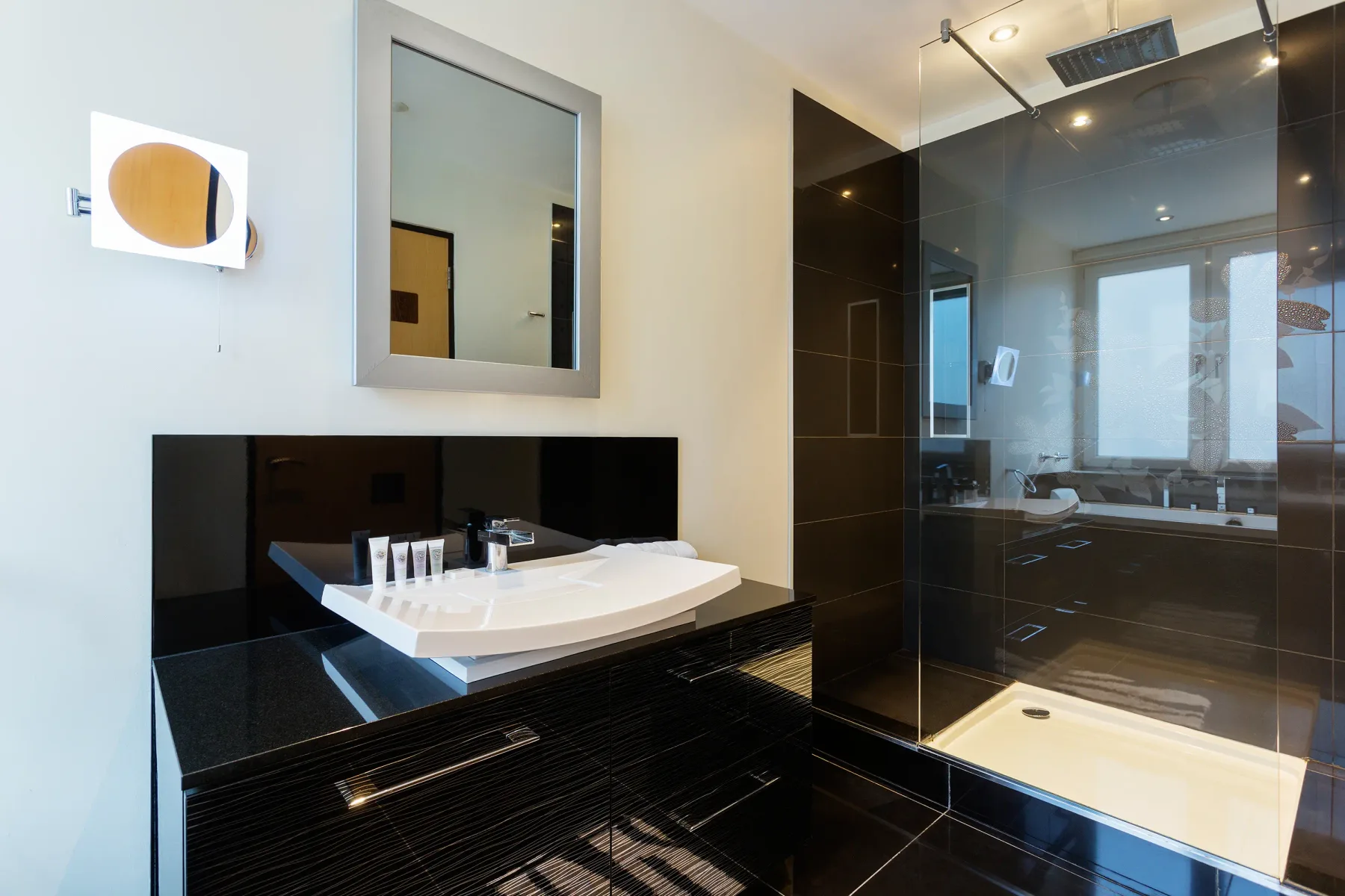 A modern bathroom with a white sink, mirror, and glass shower.
