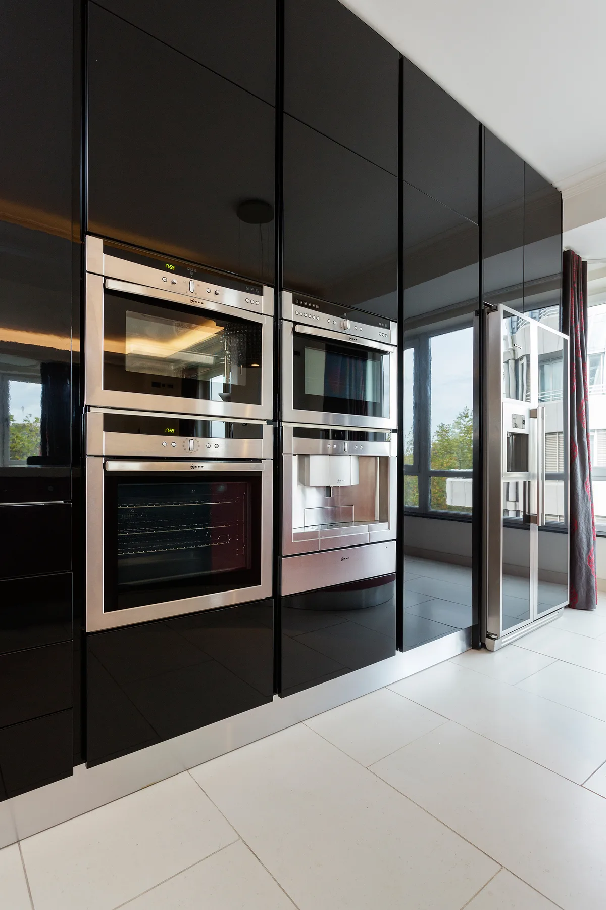 A modern kitchen with built-in ovens and a glass door opening to the balcony.