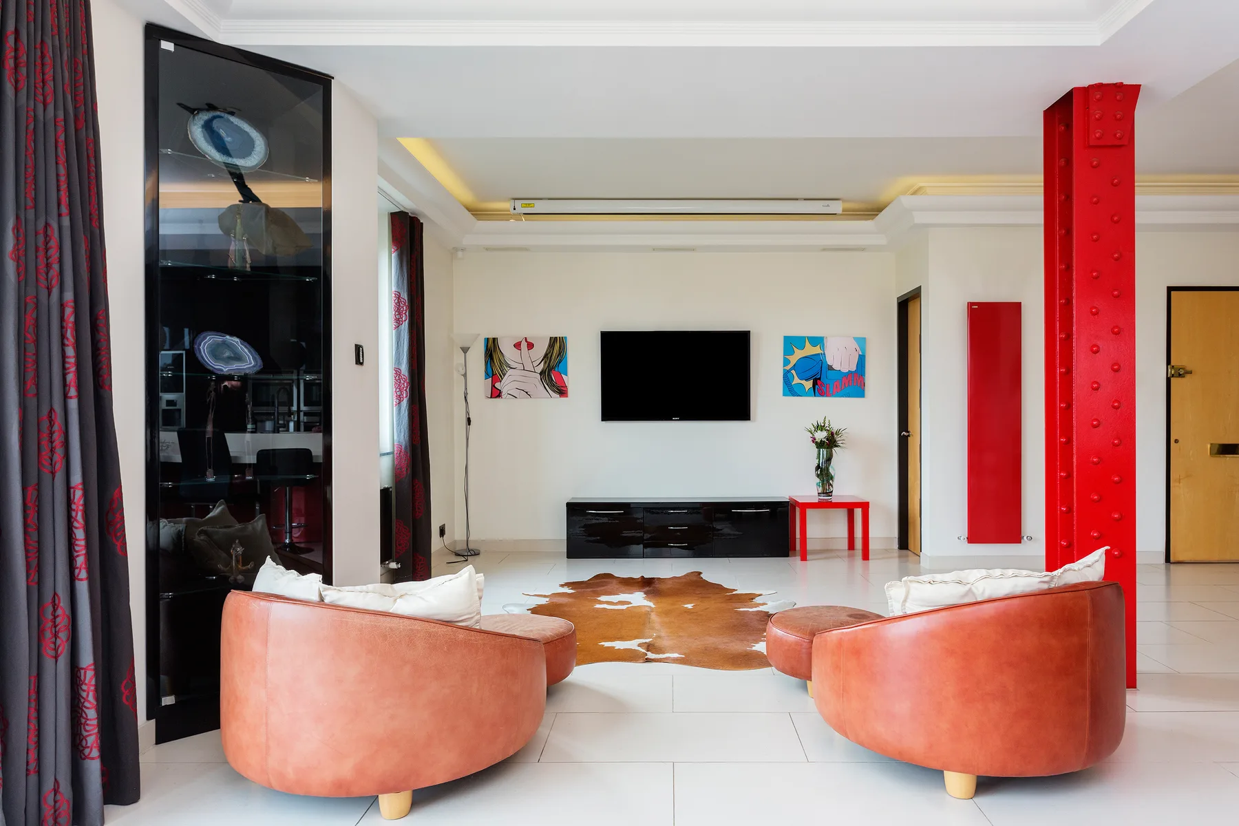 A bright living room with two curved seats facing a television and low console.