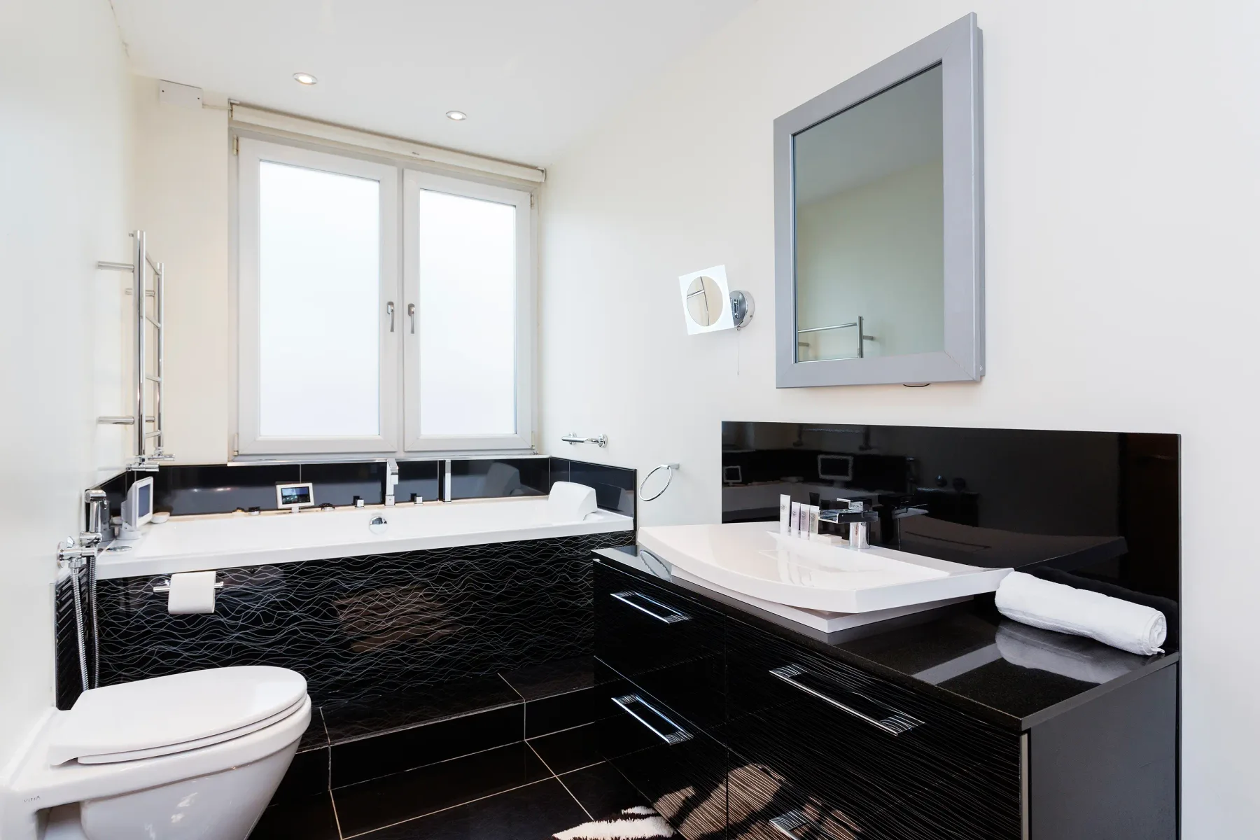 A modern bathroom with a bathtub, vanity, and large mirror.