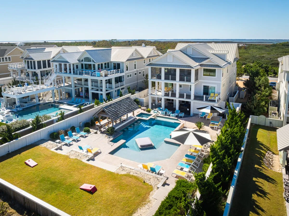 Aerial view of a shared outdoor pool area surrounded by coastal-style houses.