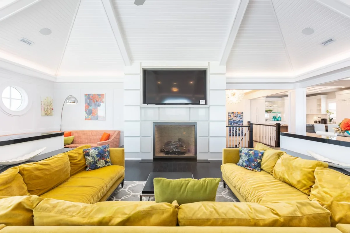 A bright living room with yellow seating arranged around a fireplace and television.