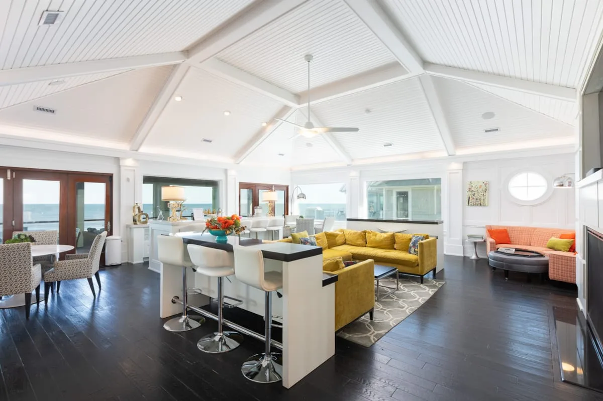 A bright open-plan living and dining area features a kitchen island and yellow seating.