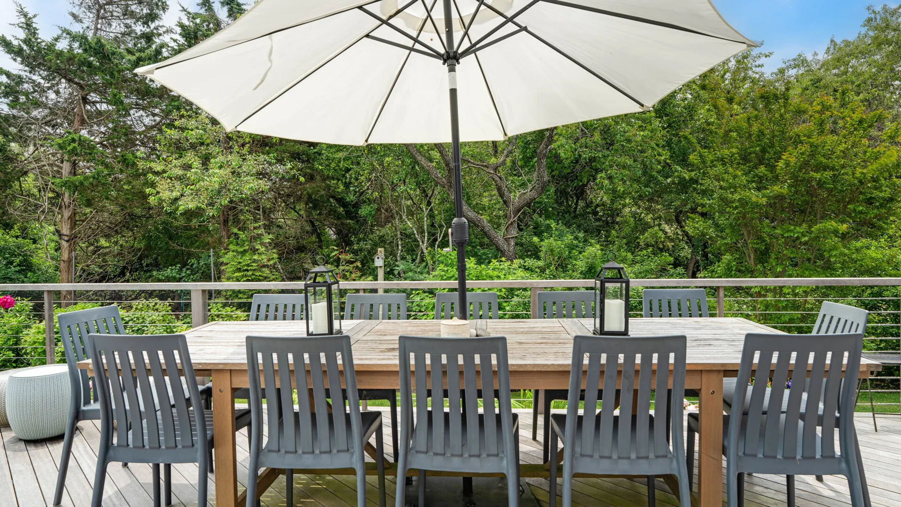 Un comedor al aire libre con asientos bajo una sombrilla grande, rodeado de vegetación.