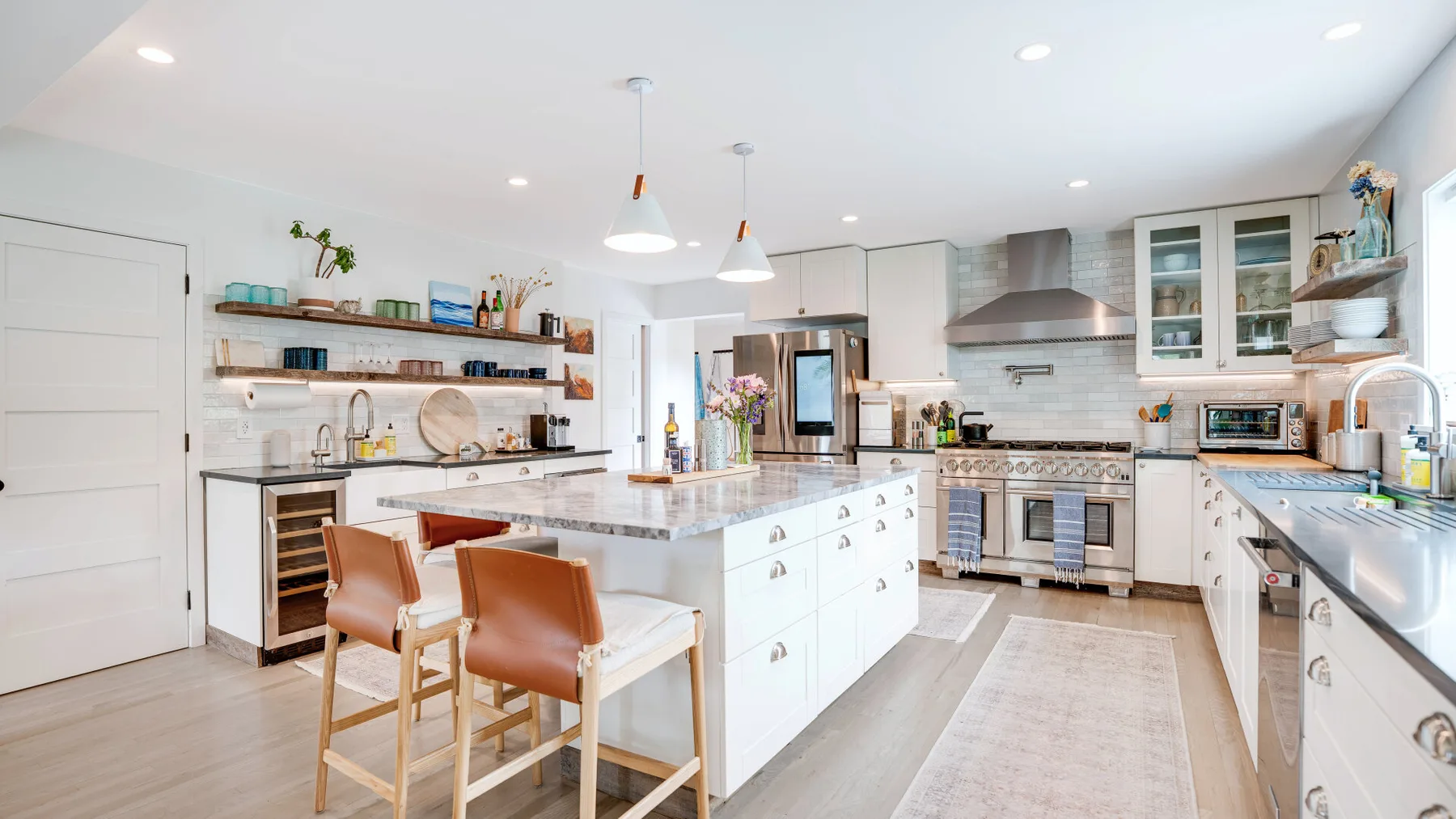 Una cocina luminosa con una gran isla central y electrodomésticos de acero inoxidable.