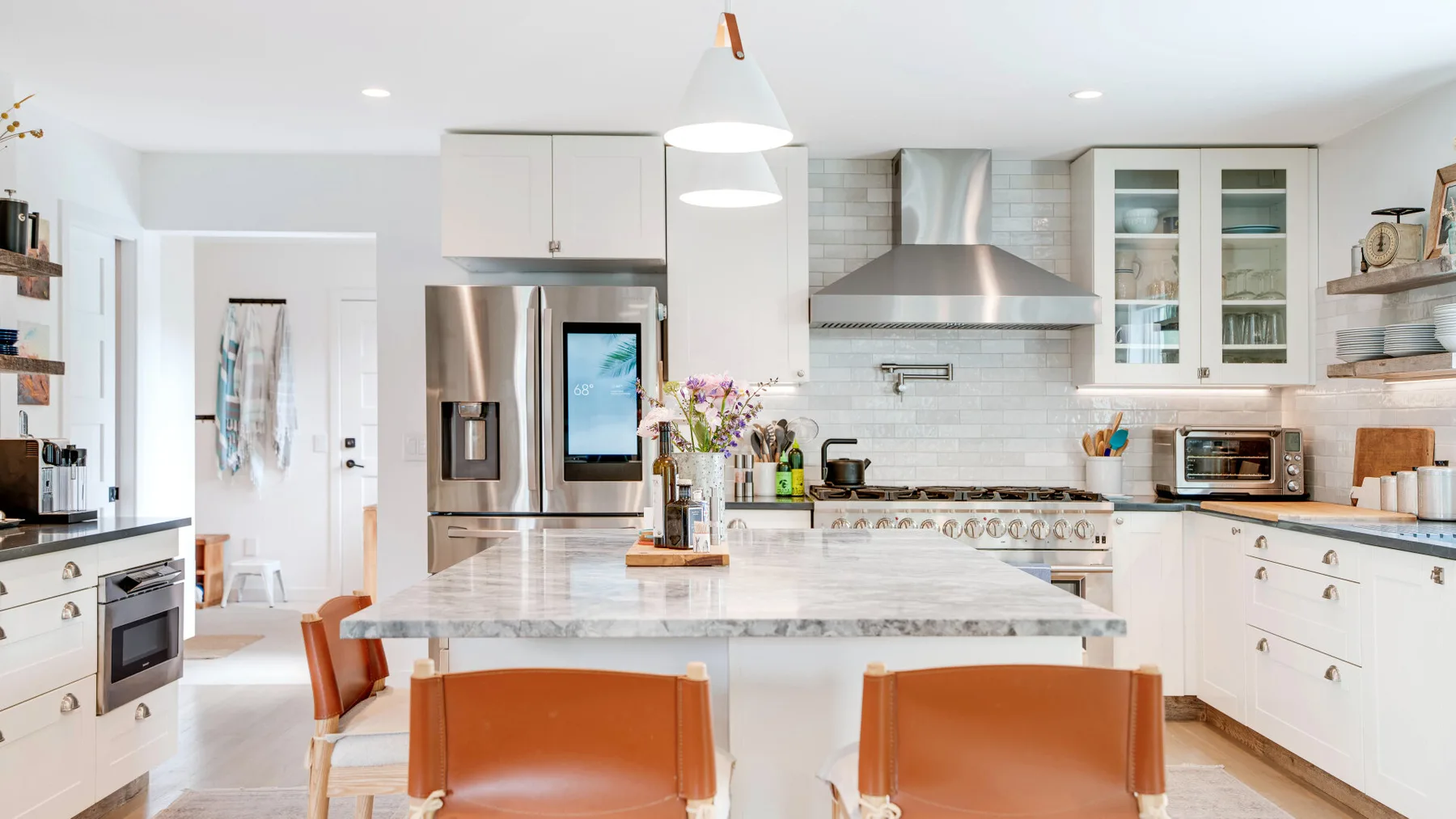 Una cocina luminosa con una isla grande y electrodomésticos de acero inoxidable.