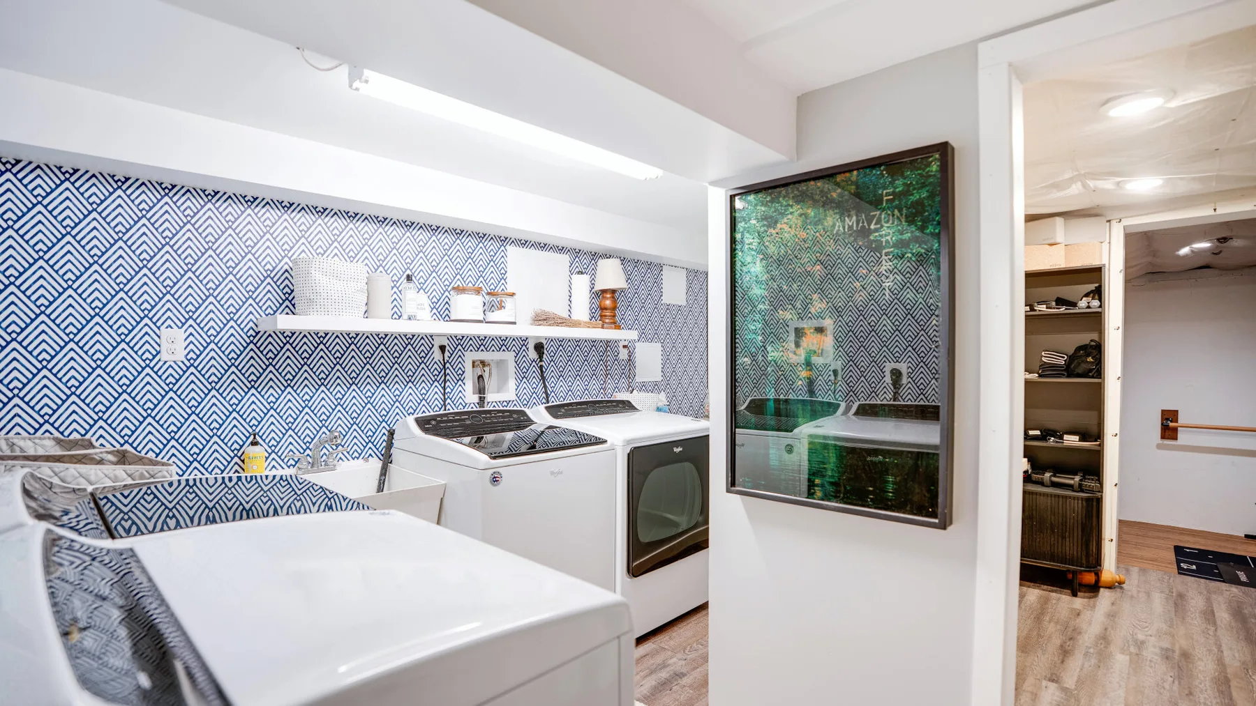 Un cuarto de lavandería con electrodomésticos de carga frontal junto a una pared estampada.
