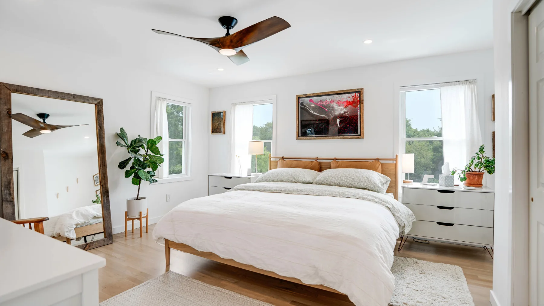 Un dormitorio luminoso con una cama bien tendida y ventanas a ambos lados.