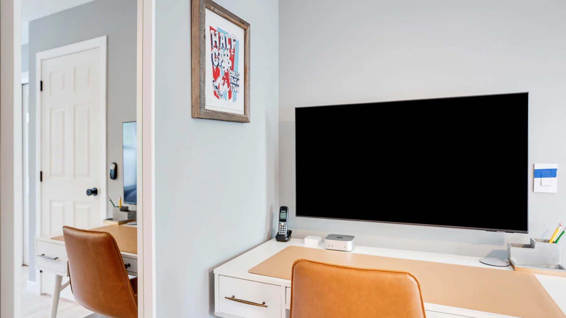 Un escritorio y asientos están frente a un televisor grande montado en la pared.