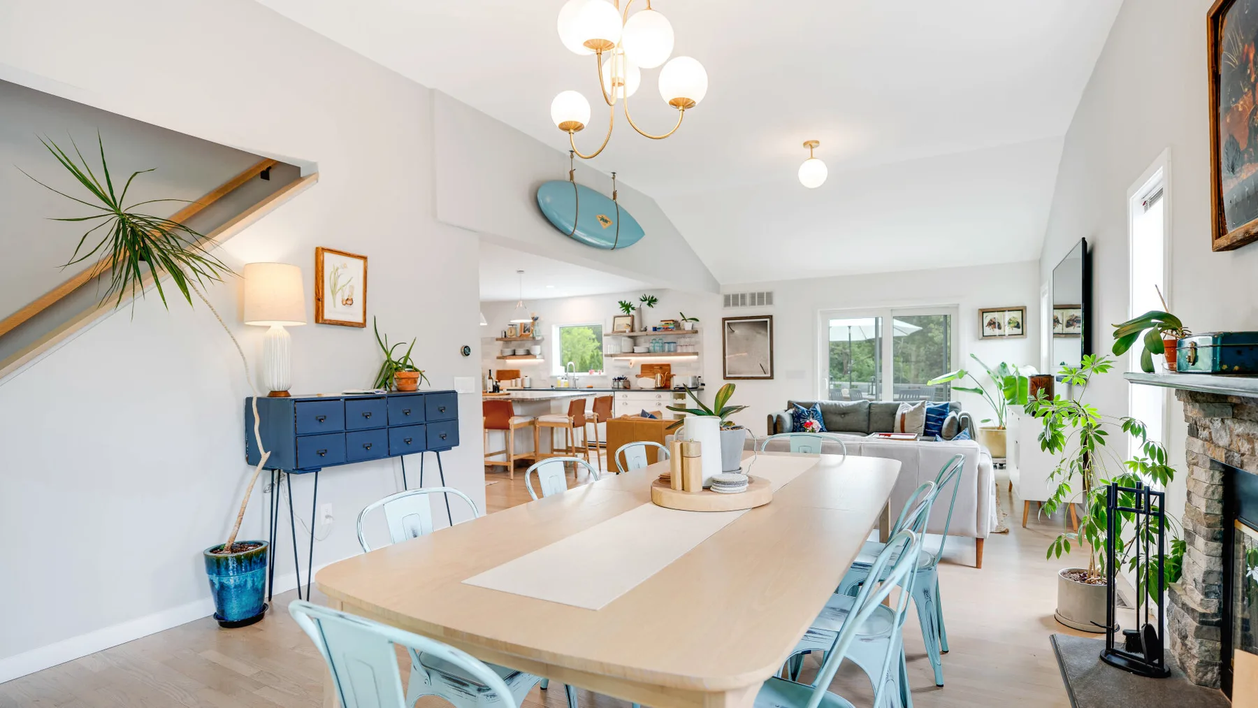 Un comedor luminoso con una mesa larga y una sala de estar al fondo.