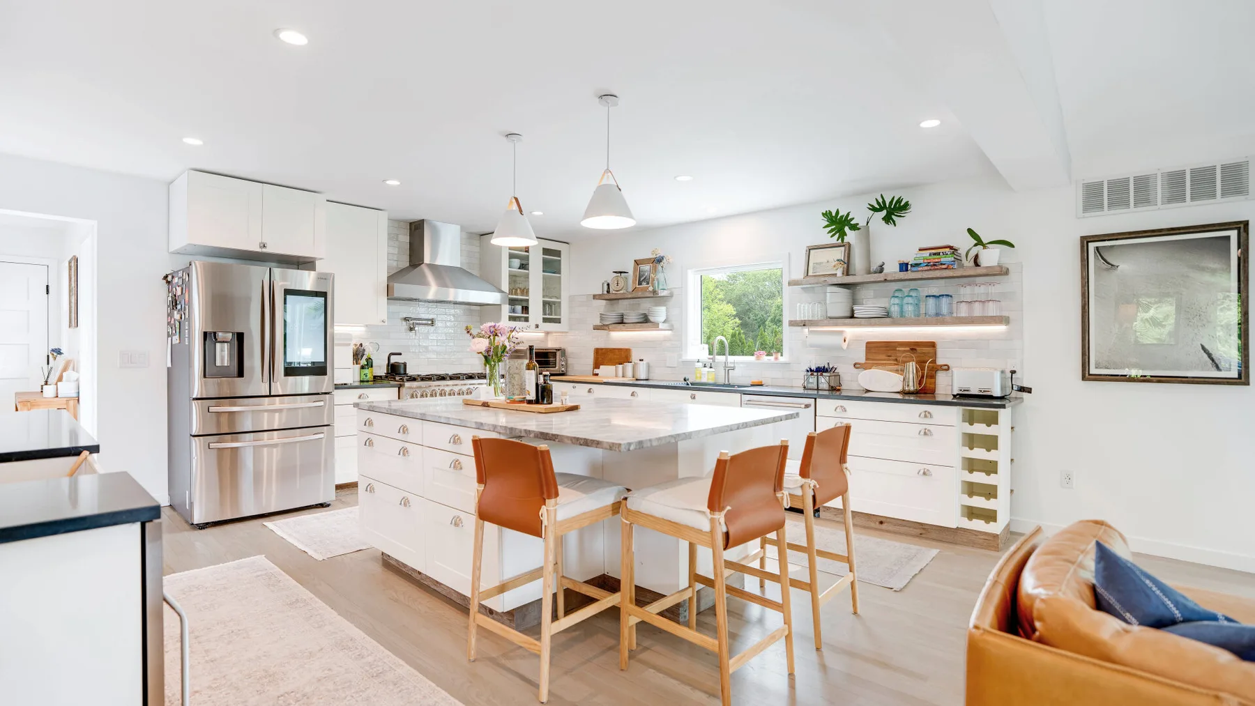 Una cocina luminosa con una isla central, electrodomésticos de acero inoxidable y asientos de madera.