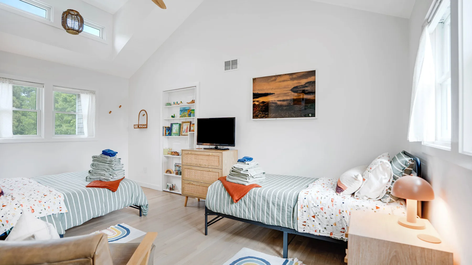 Un dormitorio luminoso con dos camas individuales y un televisor.