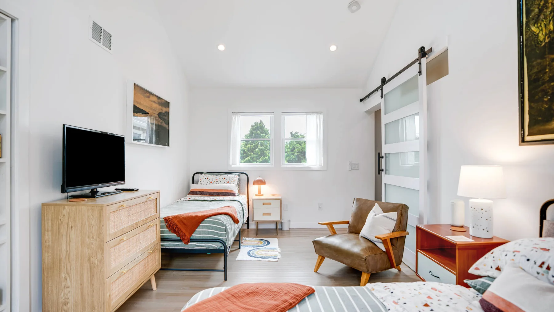 Un dormitorio luminoso con una cama, un televisor y una zona de estar.