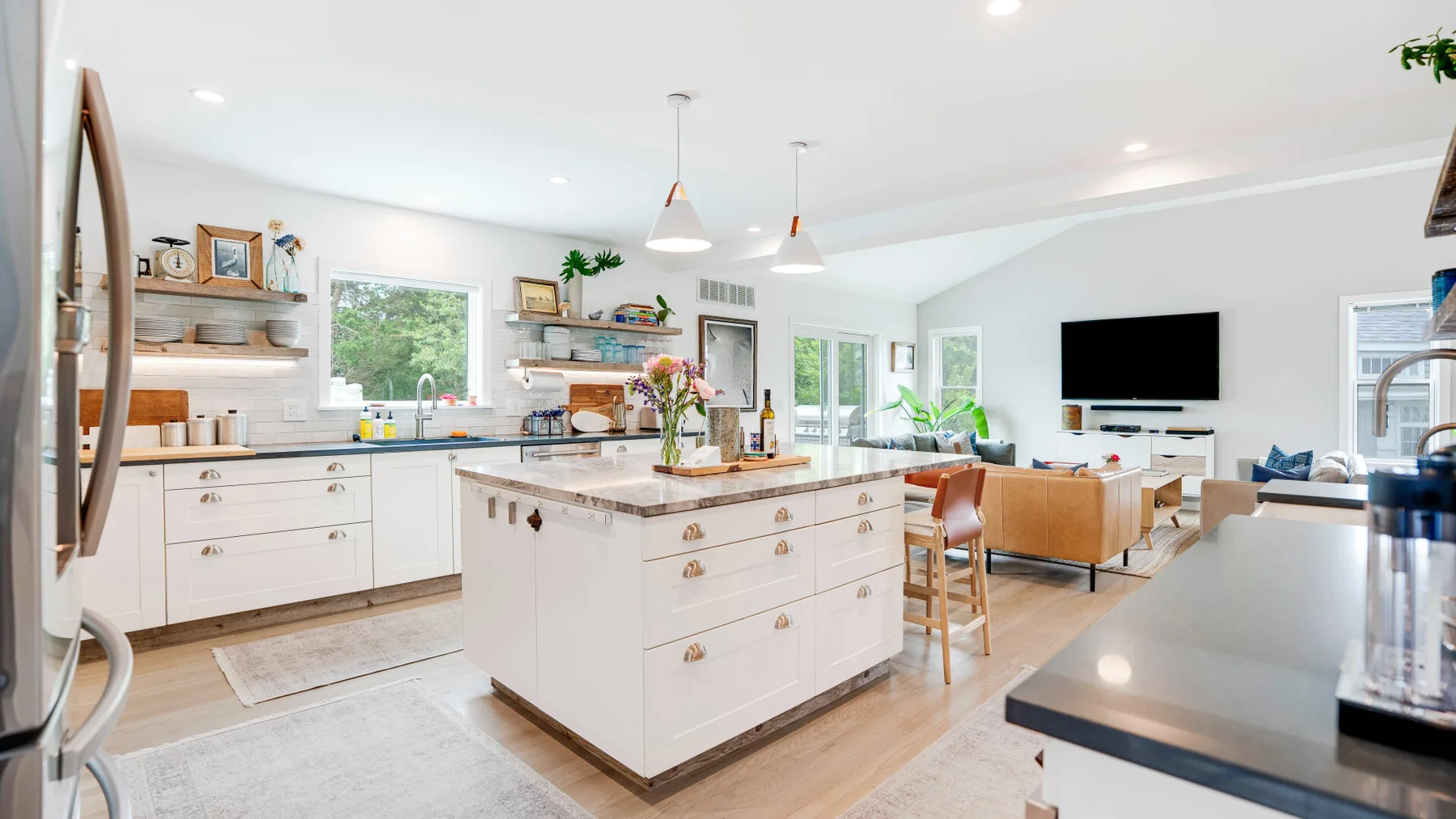 Una cocina luminosa abierta a la sala, con una isla central y asientos.