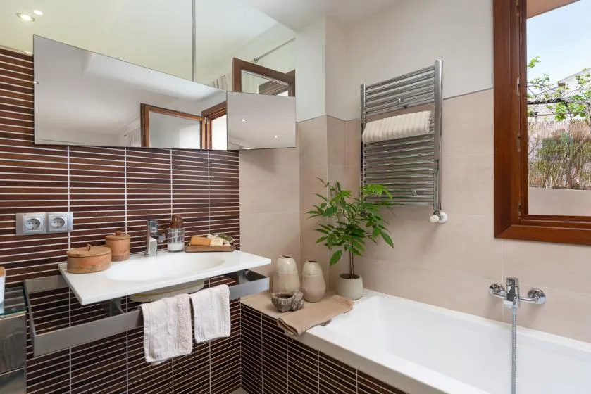 A bathroom with a bathtub, sink, and wall-mounted towel warmer.
