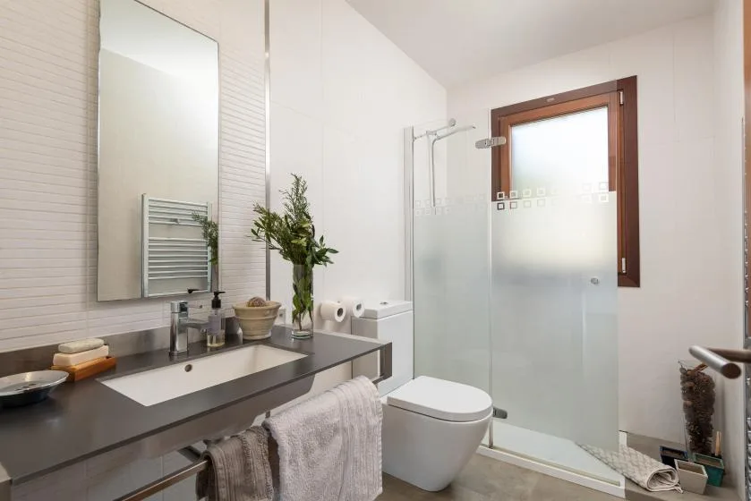 A bright bathroom with a vanity, mirror, and shower.