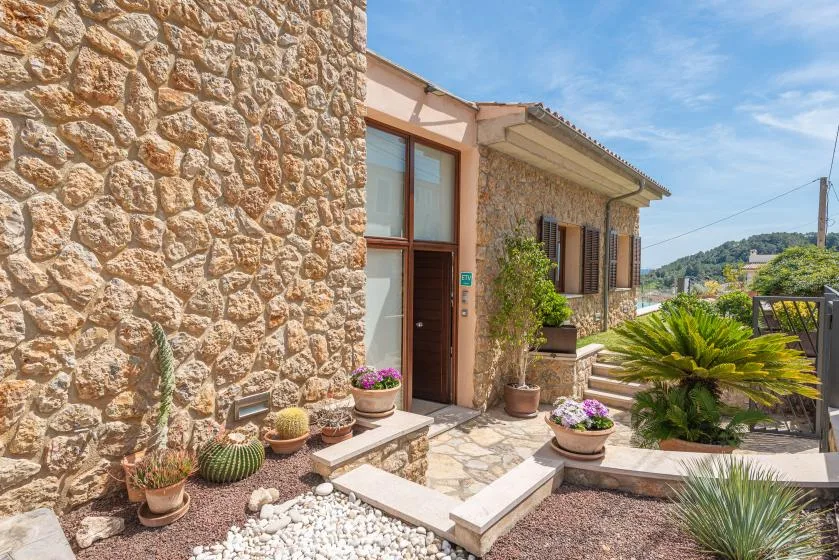 Stone house entrance with potted plants and a small landscaped courtyard.