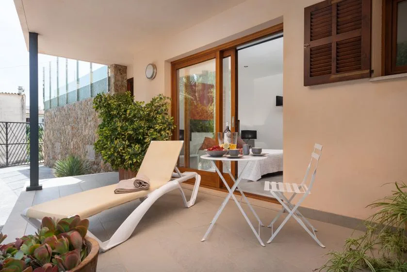 A covered patio with lounge seating and a small dining table beside sliding glass doors.
