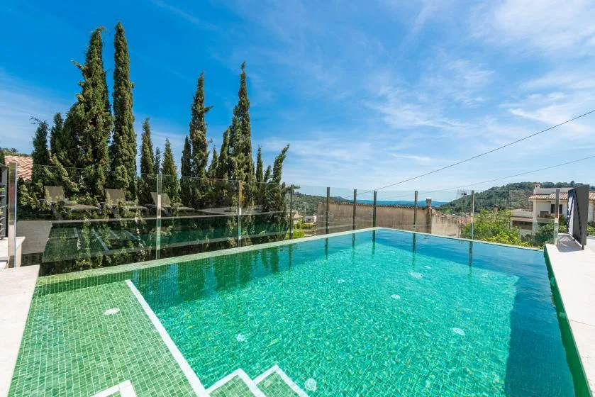 An outdoor swimming pool with clear turquoise water and hills in the background.