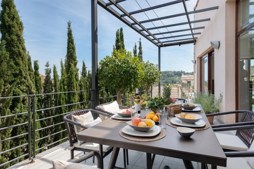 An outdoor dining terrace with a set table beneath a pergola.