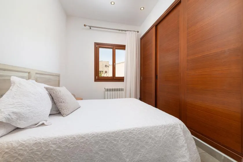 A bedroom with a bed, a window, and wooden wardrobes.