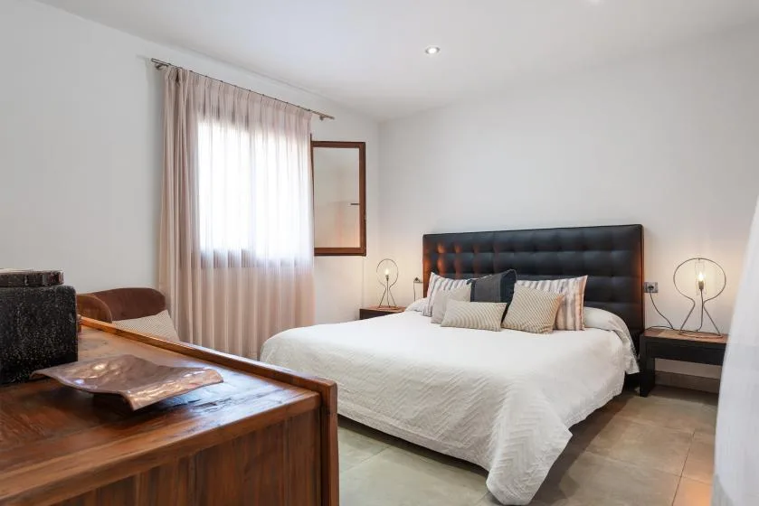 A bedroom with a large bed and a curtained window.